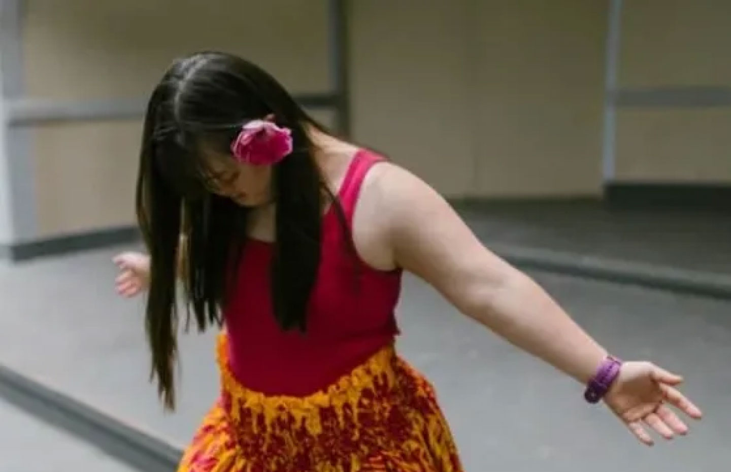 A woman with down syndrome performing a hula dance with her face facing the floor