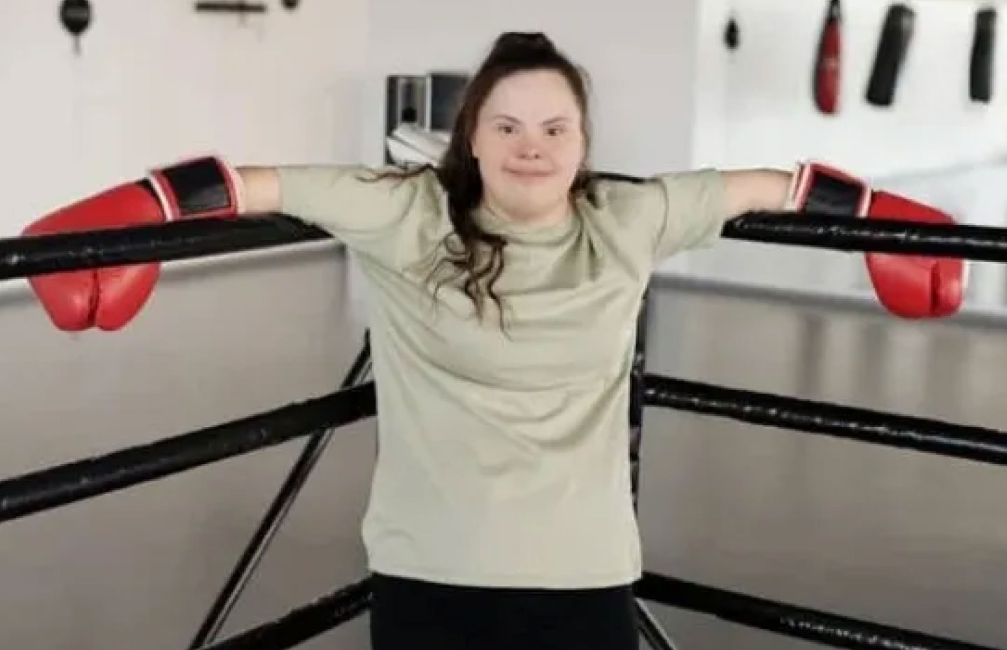 Woman with down syndrome in a boxing ring with red boxing gloves on