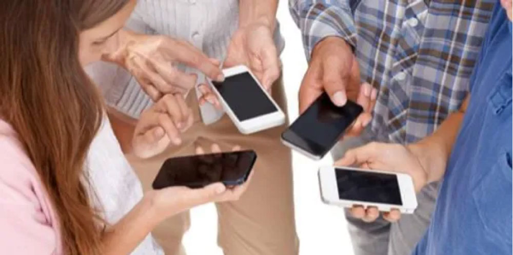 Group of people holding & looking at smartphones in a circle