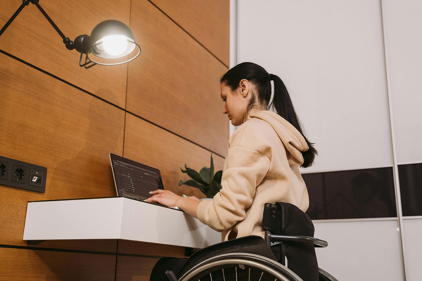 Young woman using a wheelchair typing on a laptop