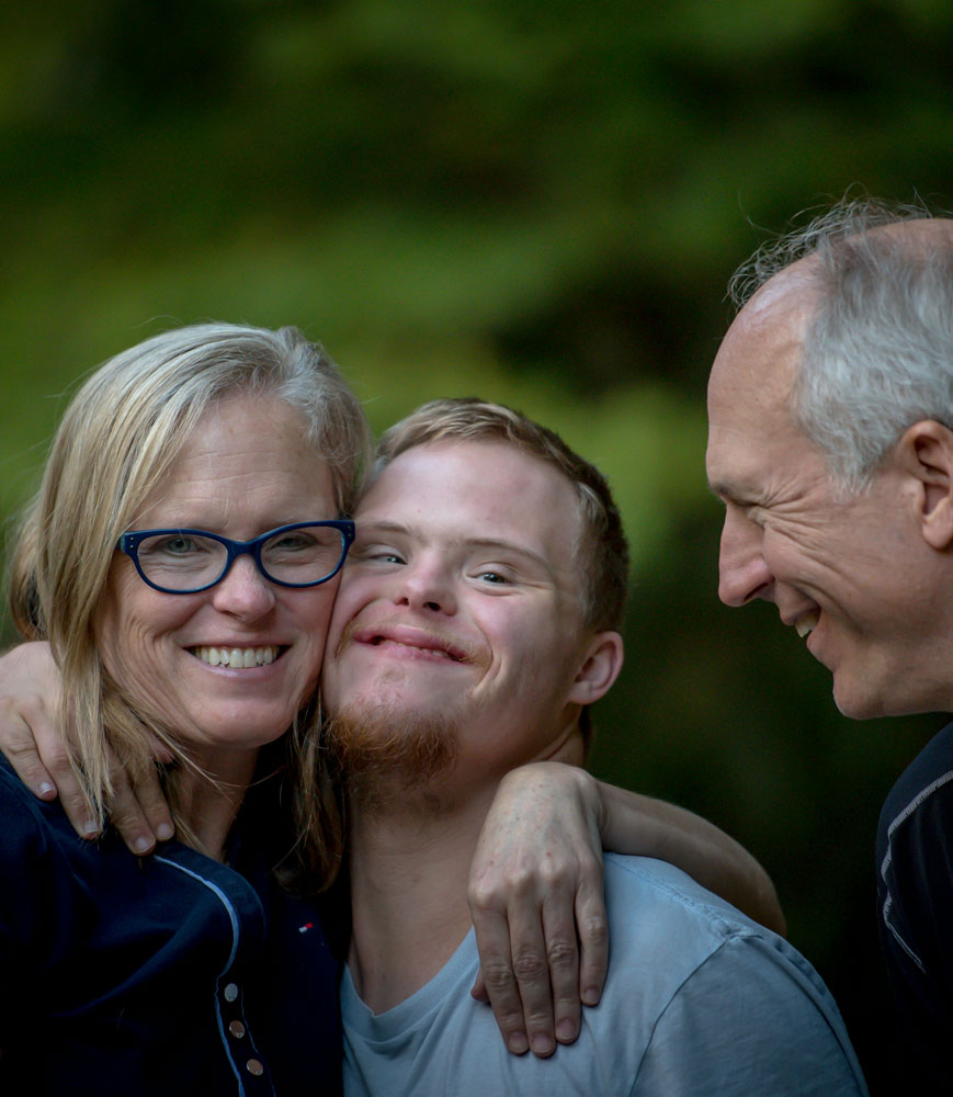 mom, dad, and son with down syndrome hugging outside