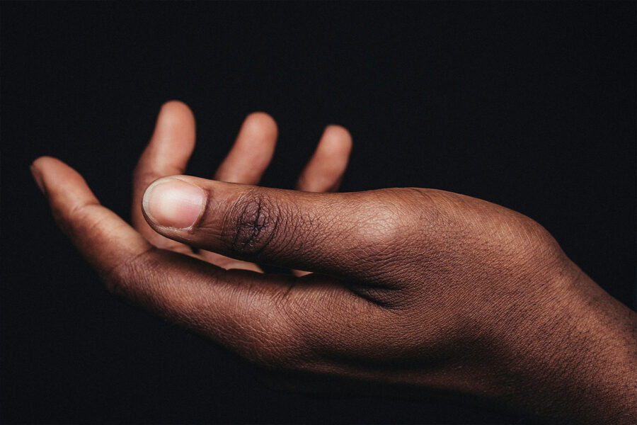 hand outstretched in front of a black background